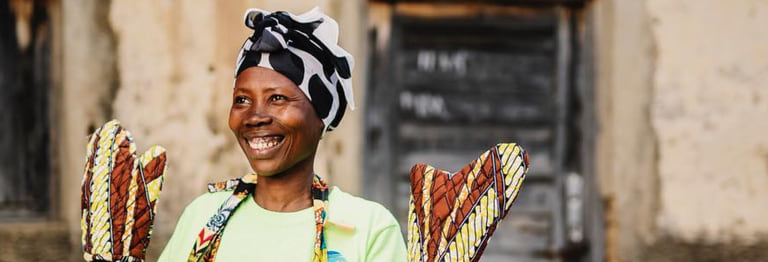 Rwandan maker holding oven mitts she stitched